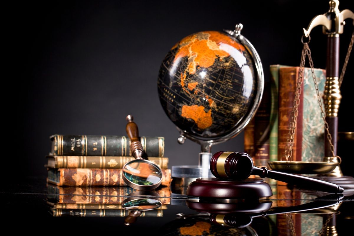 Vintage office room in a law firm with the scales of justice, legal hammer and an old globe and magnifying glass on the table with law and codex books in the background